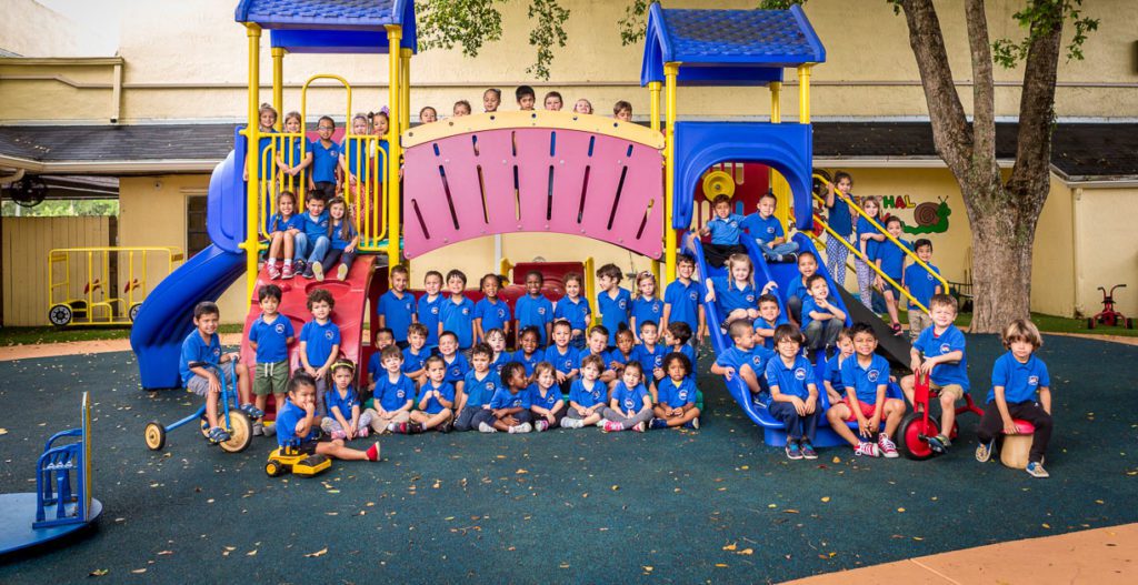 All preschoolers gather around on the slide at the playground at a Preschool & Daycare/Childcare Center serving Miami, FL.